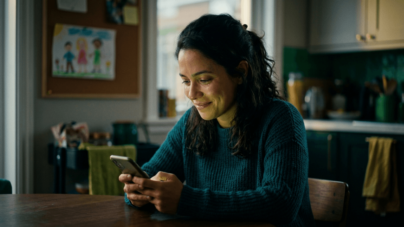 Mulher olhando o celular com expressão aliviada ao ver a confirmação de um pagamento automático de pensão alimentícia